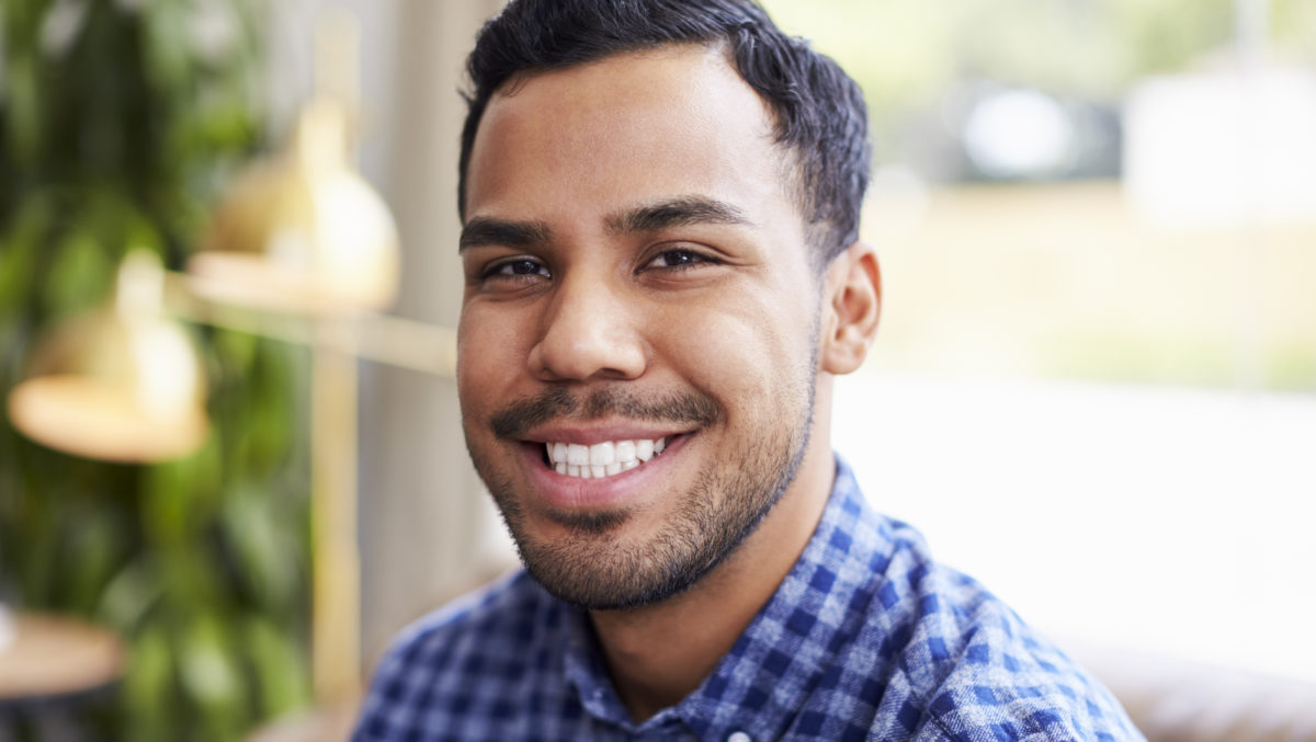 Young Hispanic man in coffee shop smiling to camera