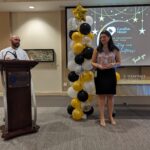 Volunteer gives a speech at the podium alongside staff member